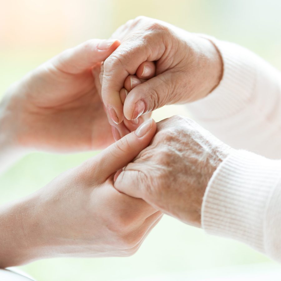 Photo with close-up of caregiver and patient holding hands